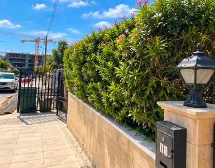 Trimmed hedge beside a limestone wall and lamp post in Limassol
